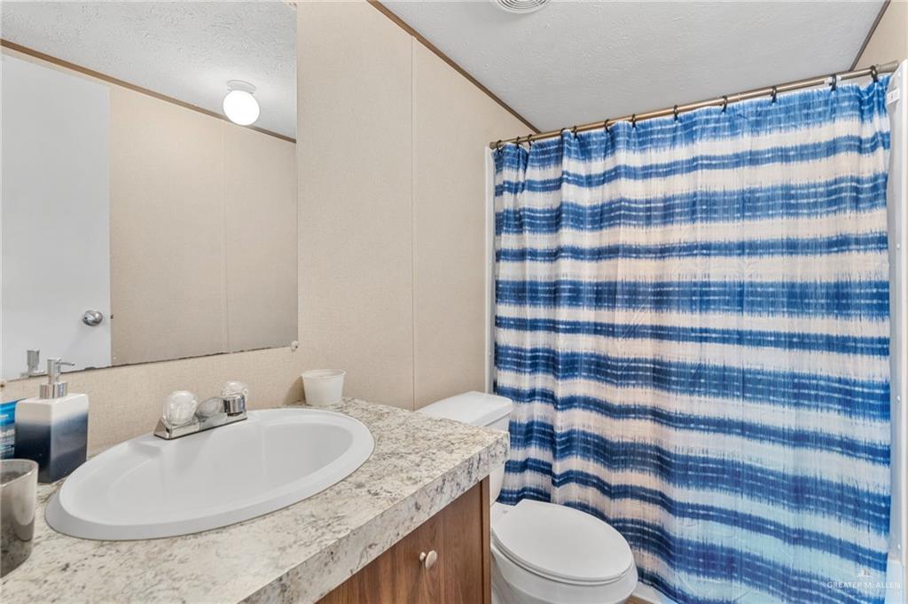 1415 Spear Street Weslaco, TX 78596 - Photo 13 of 14 a bathroom with a granite countertop sink and a mirror
