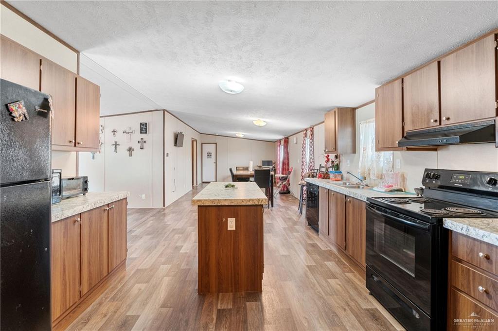 1415 Spear Street Weslaco, TX 78596 - Photo 4 of 14 a kitchen with granite countertop a stove top oven a sink dishwasher and a refrigerator with wooden floor