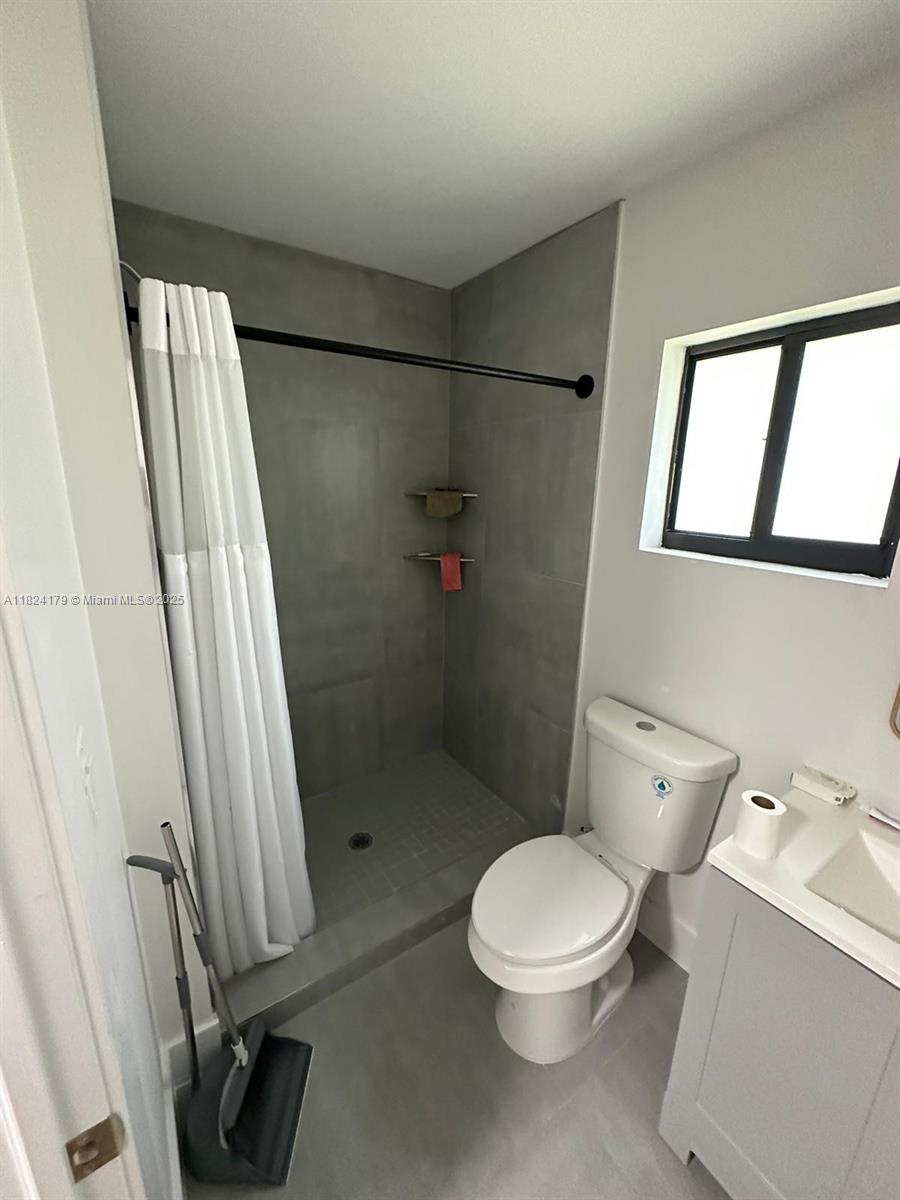 147 Northwest 61st Street Miami, FL 33127 - Photo 14 of 17 a white toilet sitting next to a bathroom sink and a shower