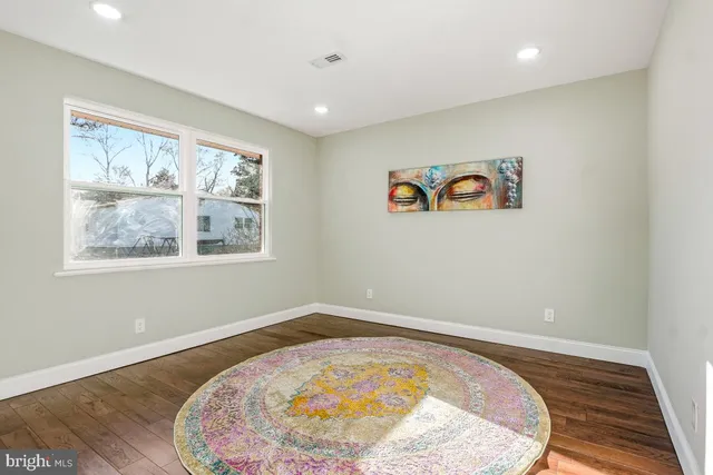 a view of an empty room with window and wooden floor