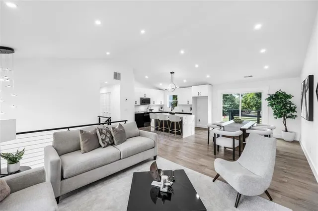 a very nice looking dining room with kitchen island stainless steel appliances furniture a large window and a chandelier