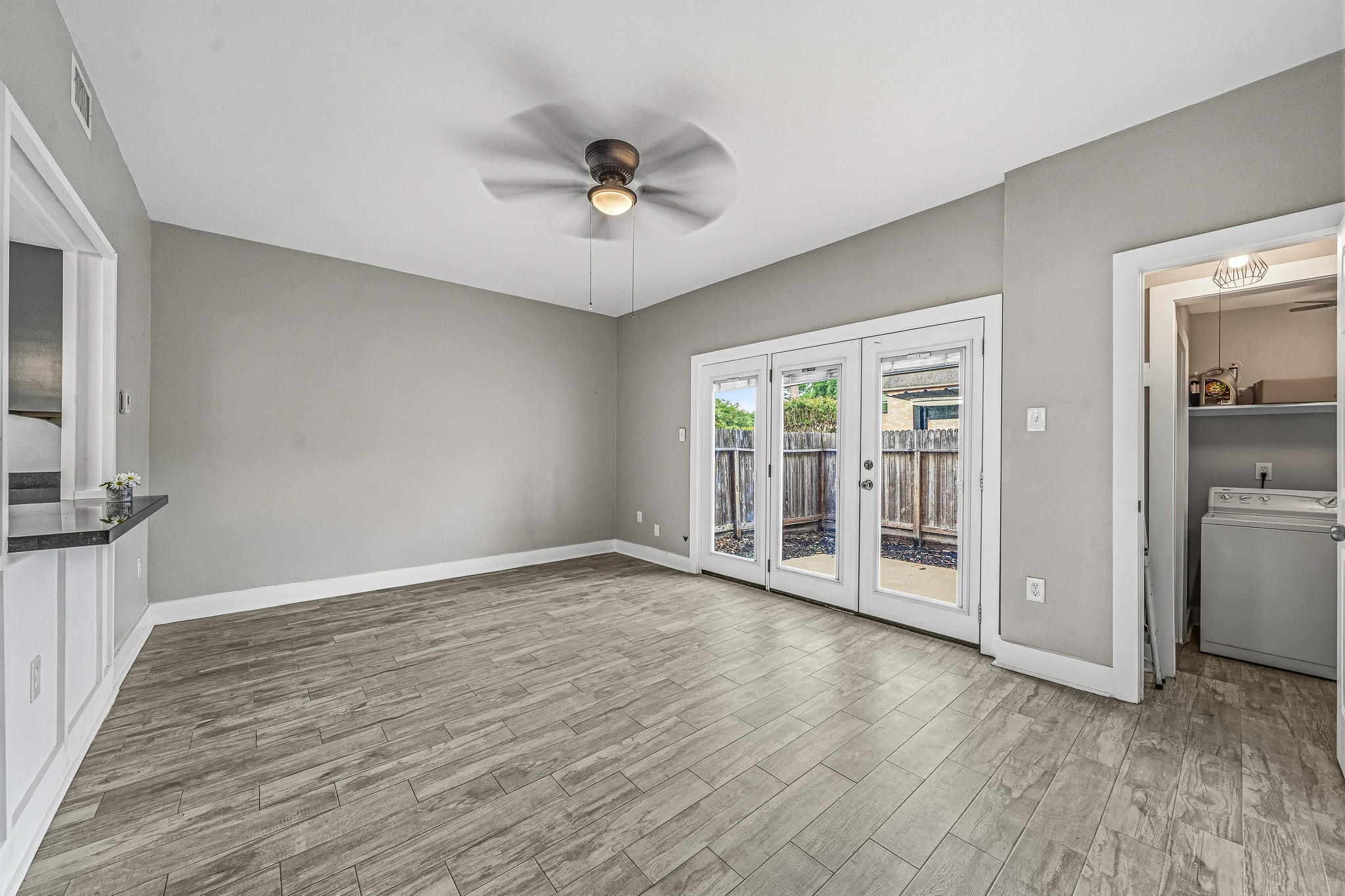 830 Threadneedle Street, Unit 240 Houston, TX 77079 - Photo 13 of 33 This room features modern wood-look tile flooring, neutral gray walls, and a ceiling fan. It has French doors leading to the backyard, offering plenty of natural light, and a convenient laundry area.