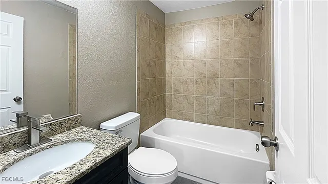 a bathroom with a granite countertop bathtub shower sink mirror vanity and toilet