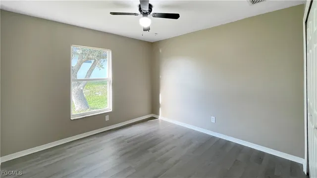 an empty room with a window and wooden floor