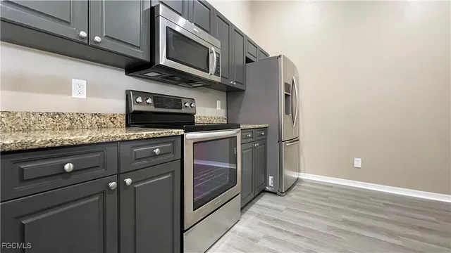 a kitchen with stainless steel appliances granite countertop a stove microwave and refrigerator