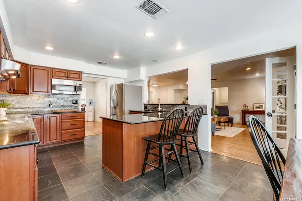 a kitchen with stainless steel appliances kitchen island granite countertop a stove a sink a dining table and chairs