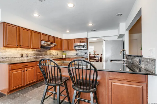 a kitchen with stainless steel appliances granite countertop a table chairs sink refrigerator and cabinets