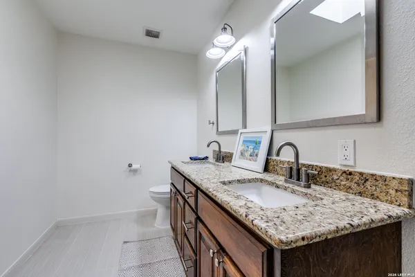 a bathroom with a granite countertop sink a toilet and a mirror