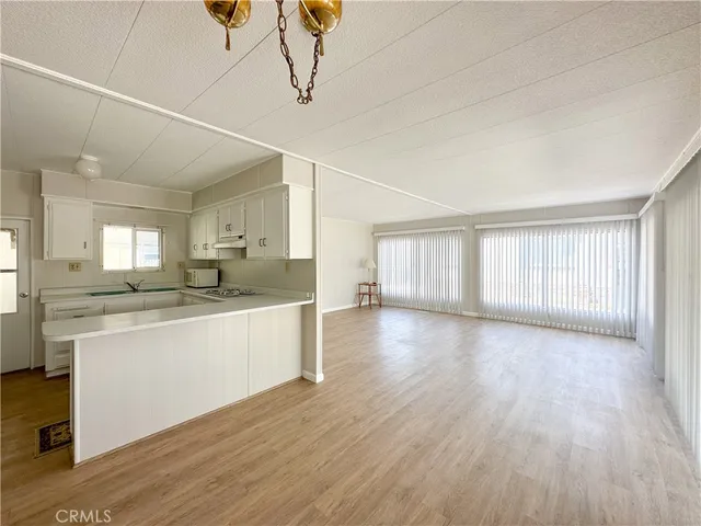 a large kitchen with kitchen island granite countertop wooden floors white cabinets and stainless steel appliances