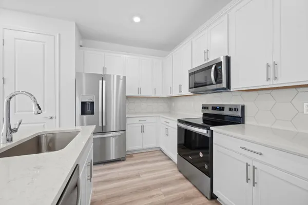 a kitchen with stainless steel appliances granite countertop a refrigerator sink and white cabinets