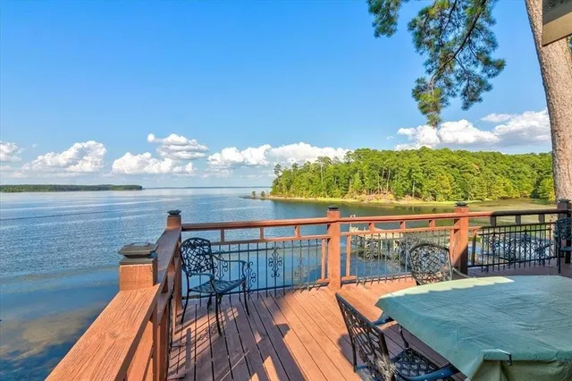 a backyard of a house with table and chairs potted plants and a large tree