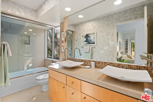 a spacious bathroom with a granite countertop sink a toilet a mirror and shower