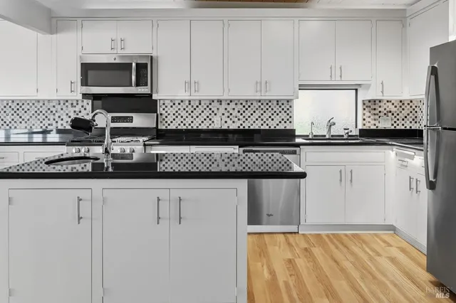 a kitchen with stainless steel appliances granite countertop a sink stove and wooden cabinets