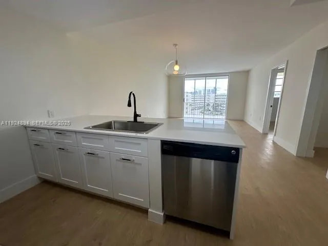 a kitchen with granite countertop a sink cabinets and wooden floor