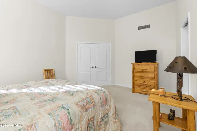 a bedroom with a bed and a flat tv screen on a dresser