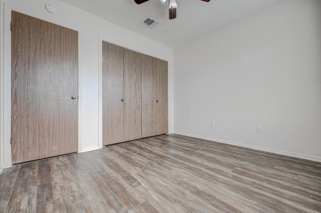 7908 West Gate Boulevard, Unit B Austin, TX 78745 - Photo 15 of 23 Unfurnished bedroom featuring wood finished floors, a textured ceiling, two closets, and a ceiling fan