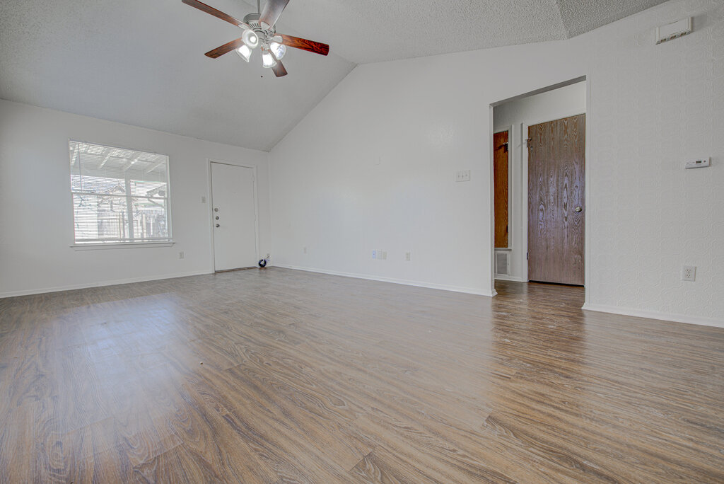 7908 West Gate Boulevard, Unit B Austin, TX 78745 - Photo 8 of 23 Unfurnished living room featuring wood finished floors, a high textured ceiling, and ceiling fan