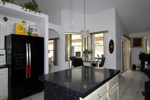 a kitchen with stainless steel appliances granite countertop a refrigerator a stove and a sink with wooden floor