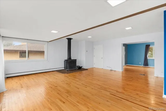 a view of an empty room with window and wooden floor