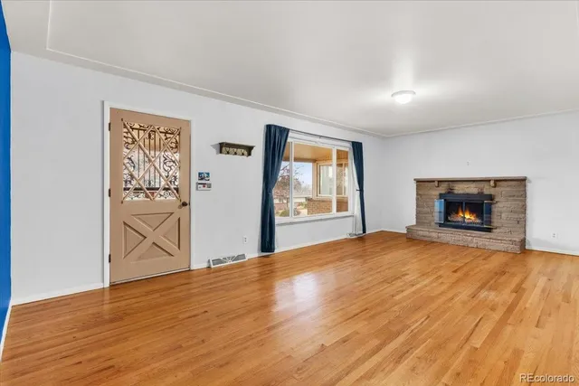 an empty room with wooden floor fireplace and windows