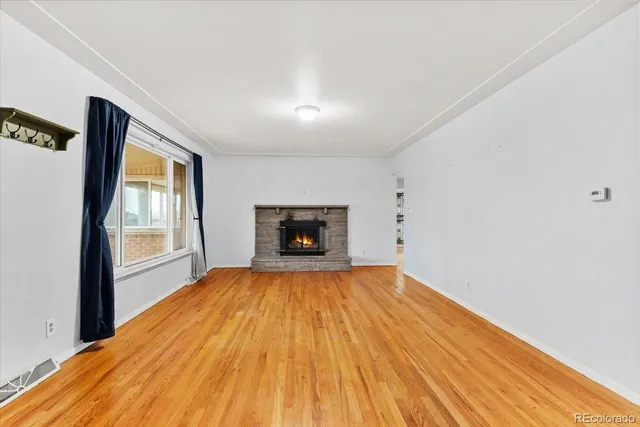 a view of an empty room with a window and wooden floor
