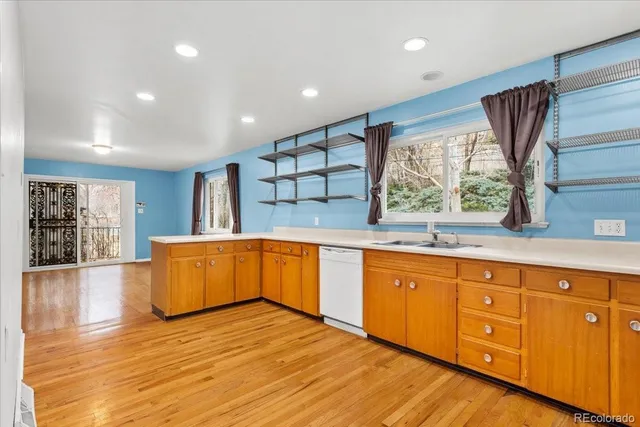 a large kitchen with stainless steel appliances granite countertop a sink dishwasher a stove and a large window with wooden floor