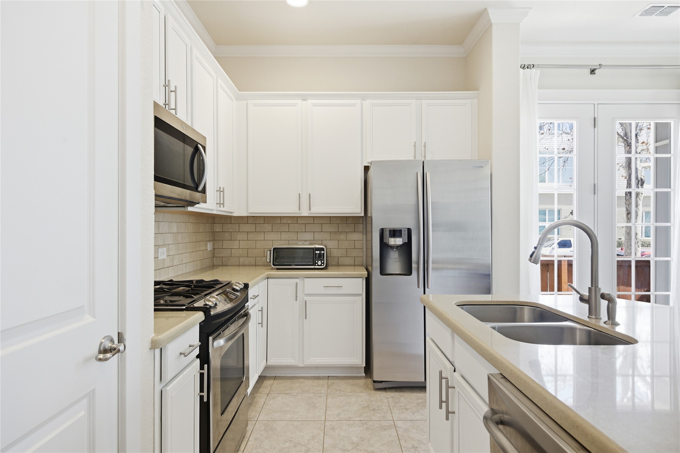 3900 Threadgill Street, Unit 2 Austin, TX 78723 - Photo 8 of 19 Tasteful backsplash, freshly painted cabinets, and modern appliances in the kitchen.