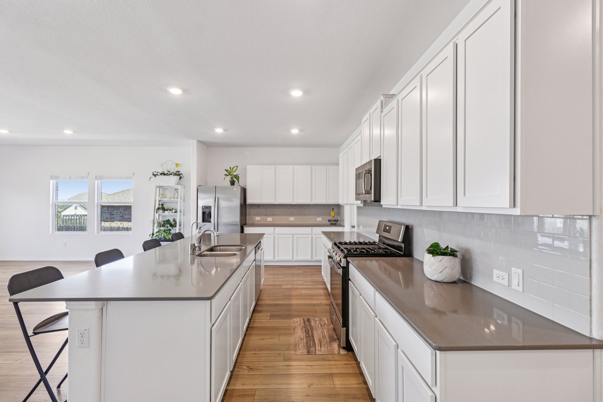 1201 Mallow Road Leander, TX 78641 - Photo 14 of 40 Kitchen with a breakfast bar, stainless steel appliances, white cabinetry, light wood-style flooring, and a spacious island