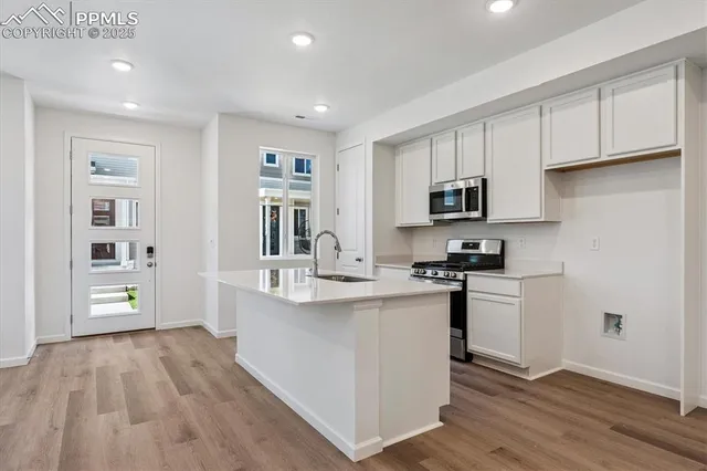 a kitchen with stainless steel appliances white cabinets a sink and a stove