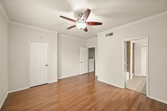 an empty room with wooden floor and ceiling fan