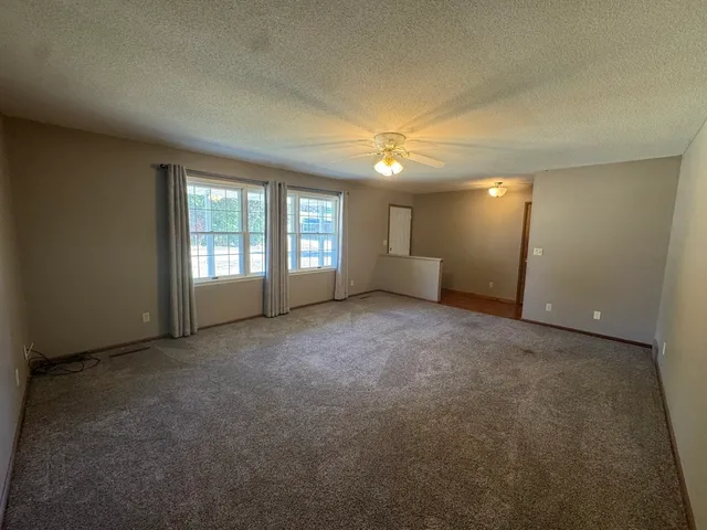an empty room with windows and ceiling fan