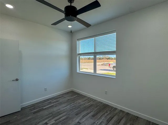 an empty room with a window and a ceiling fan