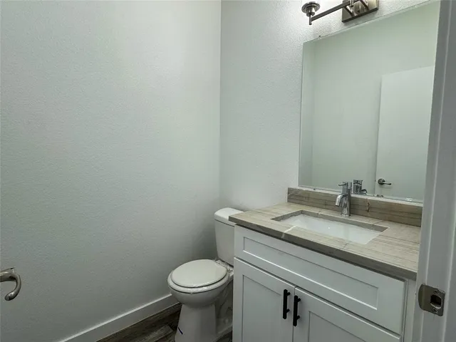 a bathroom with a granite countertop toilet and sink