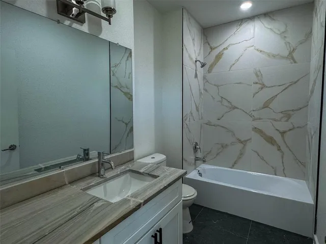 a bathroom with a granite countertop sink a toilet and shower