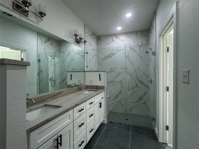 a bathroom with a granite countertop sink a mirror and shower