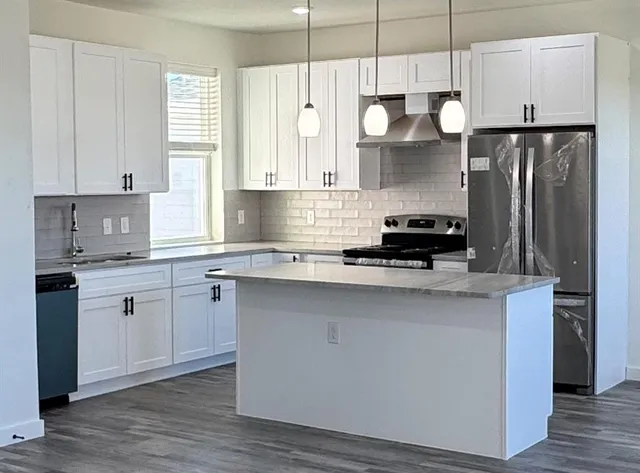 a kitchen with stainless steel appliances a stove a sink a refrigerator and cabinets
