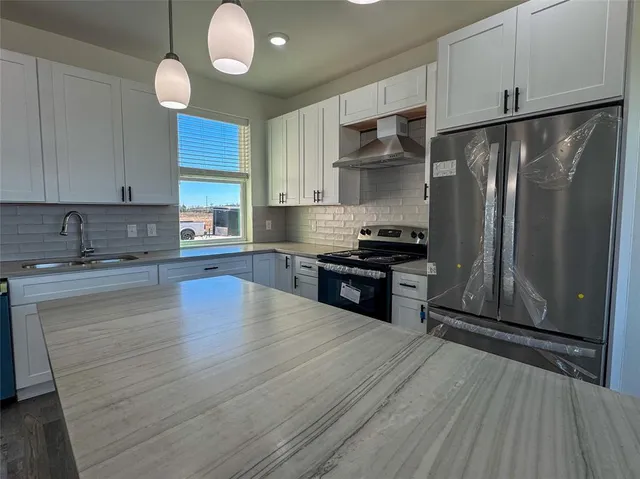 a kitchen with stainless steel appliances granite countertop a refrigerator a sink dishwasher a stove and a microwave oven on granite countertops