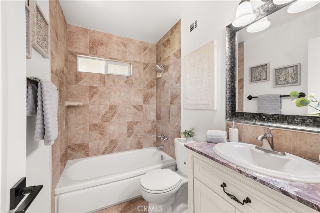 6661 Yucca Avenue Rialto, CA 92376 - Photo 22 of 44 a bathroom with a granite countertop sink a toilet a mirror a bathtub and shower