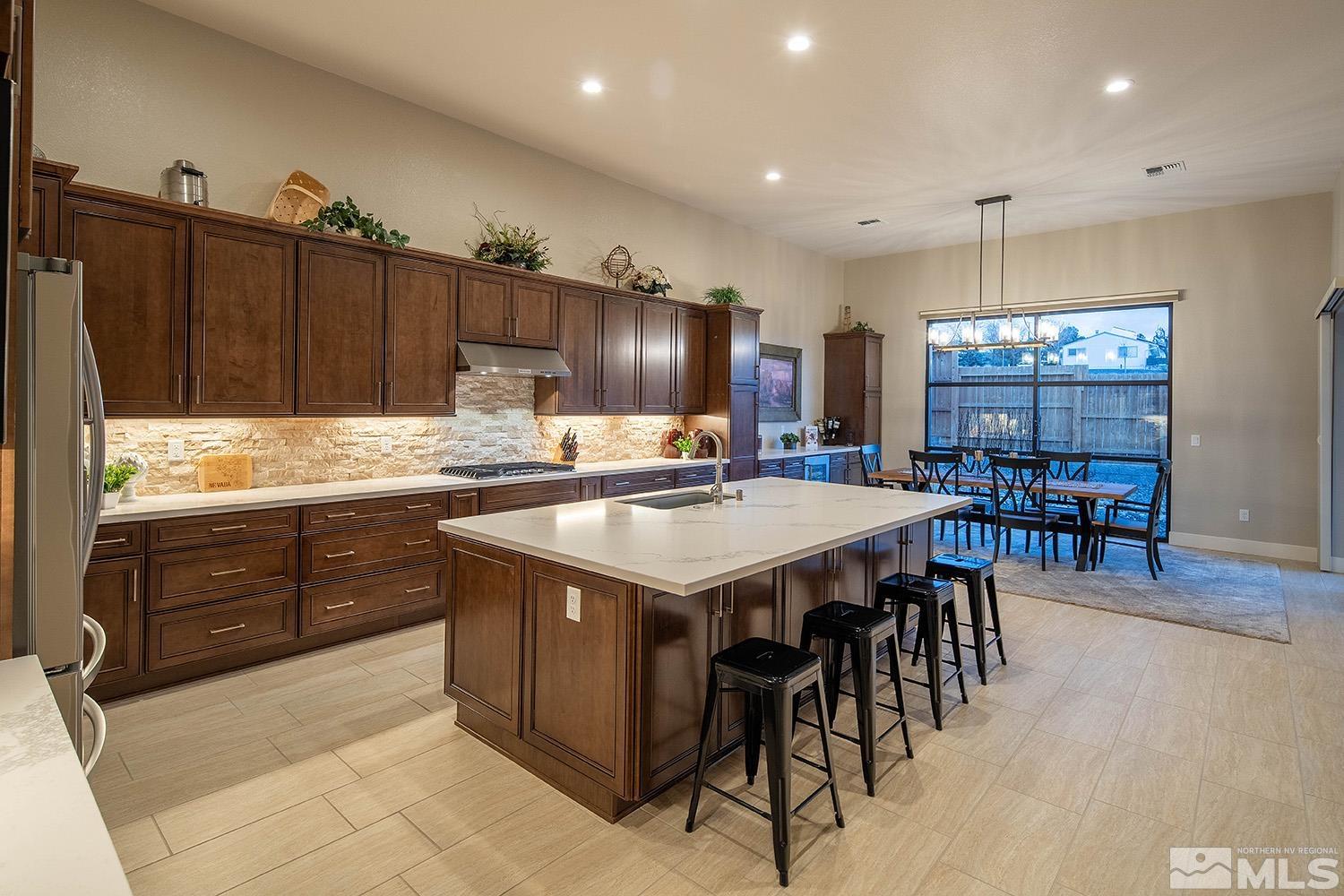3020 Feathertop Drive Reno, NV 89521 - Photo 11 of 40 a kitchen with stainless steel appliances granite countertop a table chairs and a refrigerator
