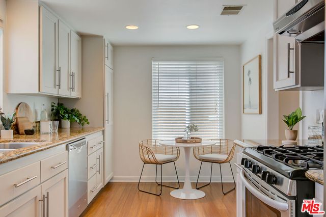 a kitchen with stainless steel appliances kitchen island wooden floors and white cabinets