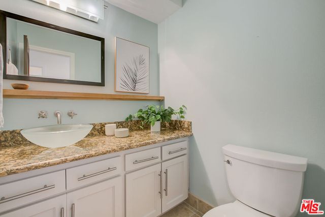 a bathroom with a granite countertop toilet sink and mirror