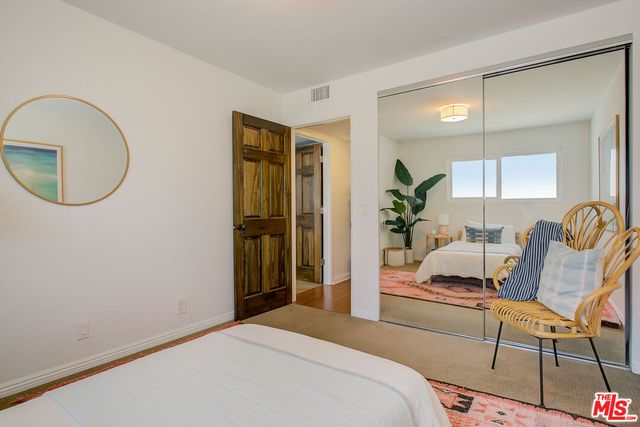 a bedroom with a bed wooden floor and a mirror