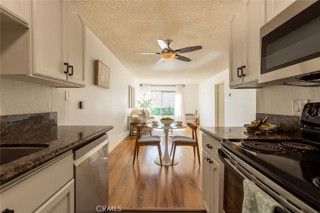 a kitchen with granite countertop a stove a sink a dining table and chairs with wooden floor