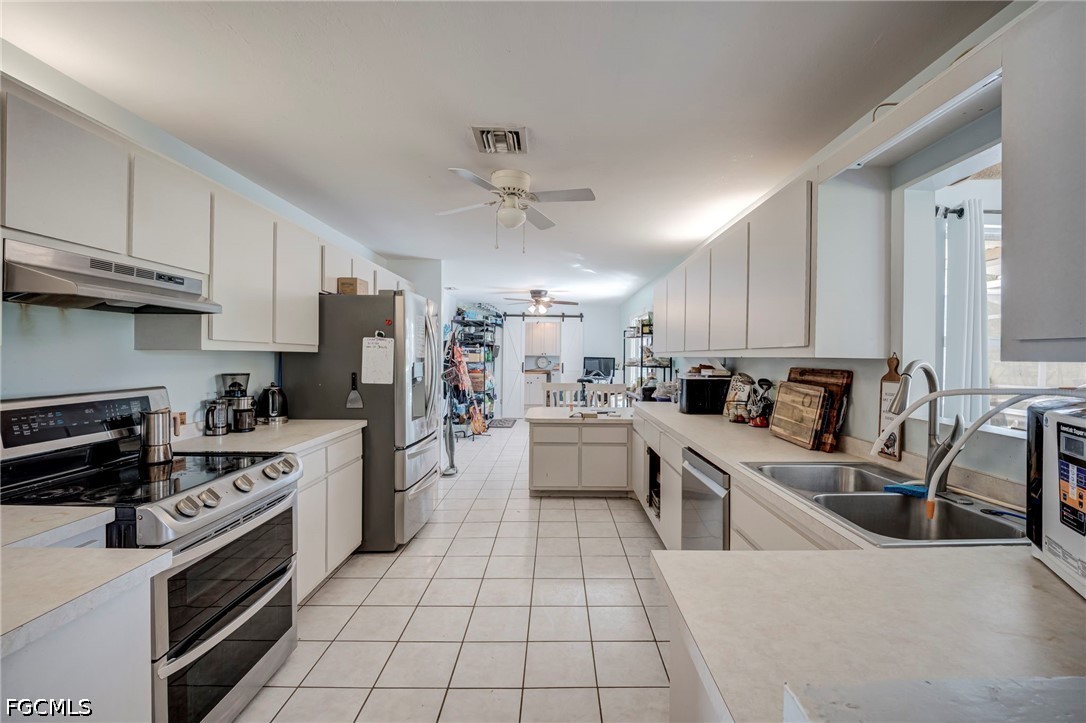 4110 East 23rd Street Alva, FL 33920 - Photo 10 of 38 a kitchen with stainless steel appliances a stove a sink cabinets and a refrigerator