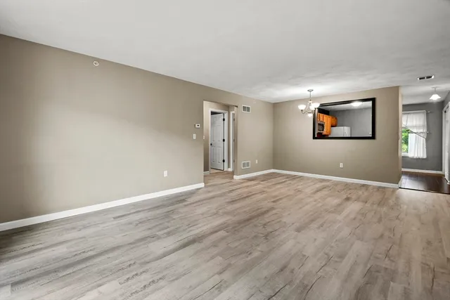 an empty room with wooden floor and window
