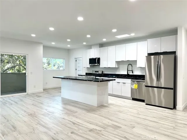 a kitchen with granite countertop a refrigerator and a stove top oven