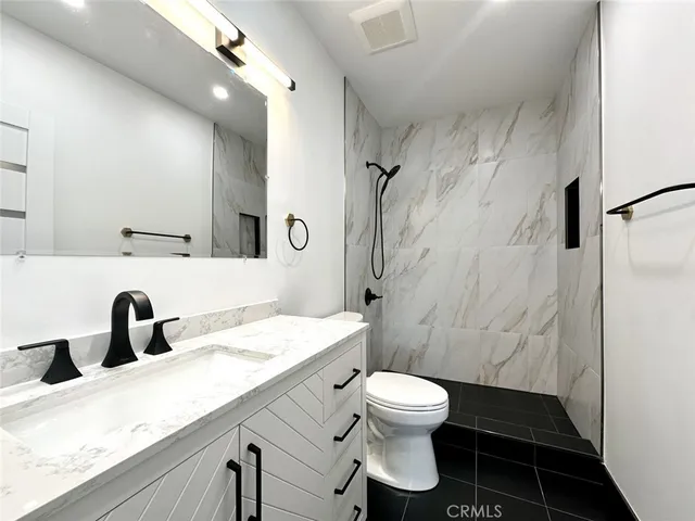 a bathroom with a granite countertop sink toilet a mirror and shower