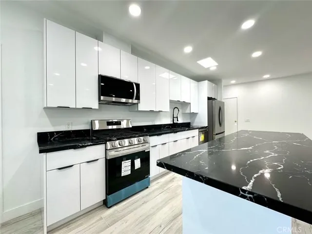 a kitchen with stainless steel appliances granite countertop a stove a sink and a microwave