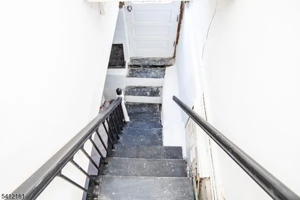 a view of staircase with railing and white walls