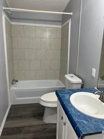 a bathroom with a granite countertop bathtub sink vanity mirror and toilet